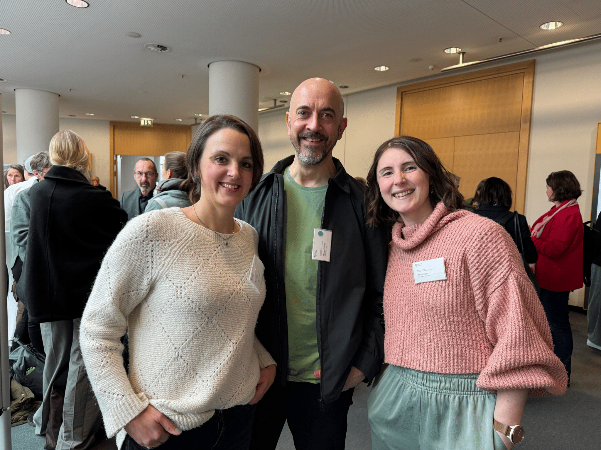 2 Frauen und ein Mann lächeln in die Kamera